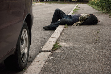 Drunk man lying outdoors. Unconscious person in the street. Poverty and alcoholism.