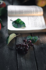 Autumn still life: Grapes with a book on a wooden background.