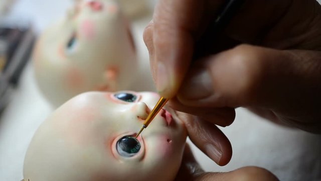 Master puppeteer draws eyes for dolls. Made the doll's eye with a brush and paint.