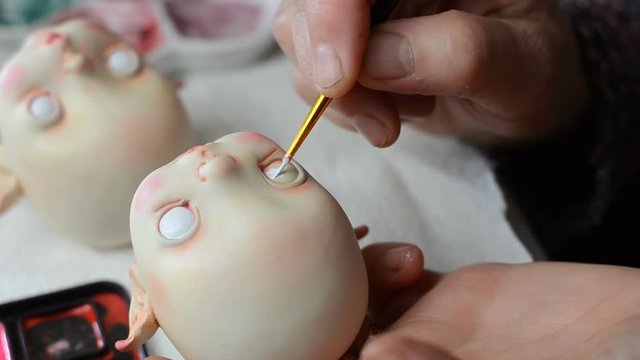 Master puppeteer draws eyes for dolls. Made the doll's eye with a brush and paint.