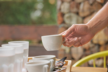 Cropped hand of man takes a cup of coffee from the tray with drinks. Serving outdoor coffee