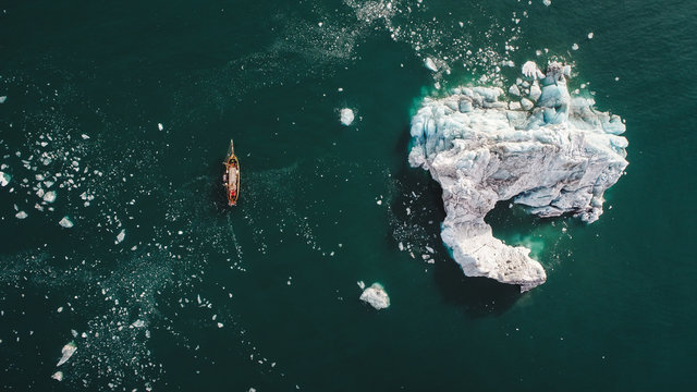 Aerial view if sailboat sailing near iceberg in sea