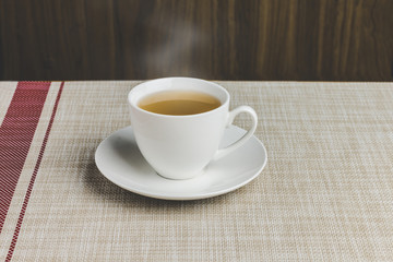 Cup of tea on tablecloth and wooden background