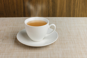 Cup of tea on tablecloth and wooden background