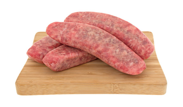 Several mild bratwurst sausages on a wood cutting board isolated on a white background.