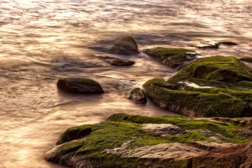 Sea water dripping between rocks during summer sunset