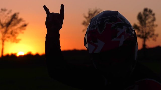 motocross rider devil horns rock on and head bang sunset 4k slow motion