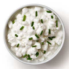 White ceramic bowl of chunky cottage cheese garnished with chives isolated on white from above.
