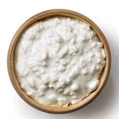 Wooden bowl of chunky cottage cheese isolated on white from above.