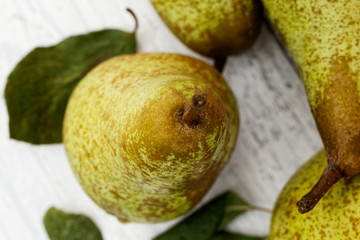 Closeup of abate fetel pear with leaves on white painted wood from above.