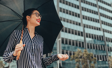 Smiling businesswoman outdoors with umbrella