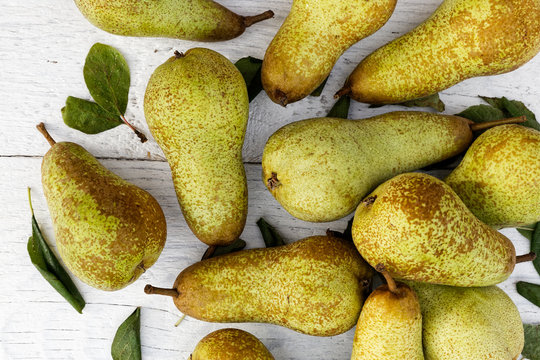 Abate fetel pears with leaves on white painted wood from above.