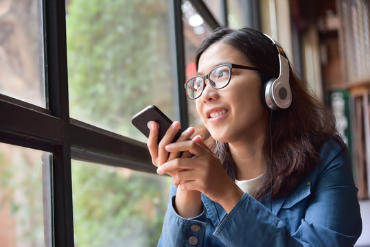 Asian woman listening to the music with headphone.