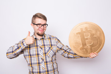 Happy cheerful young man holding big golden bitcoin on white background. Crypto currency, virtual money, internet and economics concept