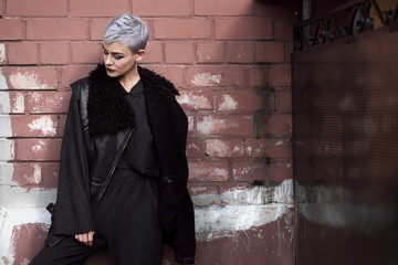 Young beautiful fashion girl shooting outdoors near brick wall at home