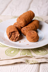 Homemade healthy vegan chocolate truffles with dates, coconut flakes and rolled oats served on white plate