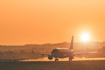 Fototapeta na wymiar Passengers airplane landing to airport runway in beautiful sunset light.