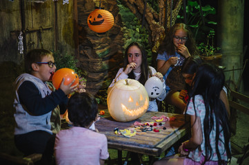 Group of friends in the party with pumpkin, candies and soft drinks