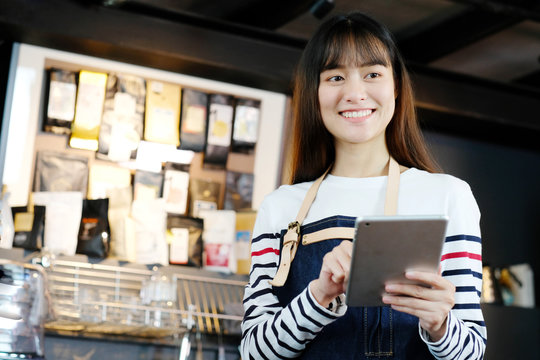Young asian woman, barista, using tablet to order coffee at cafe counter background, food and drink concept