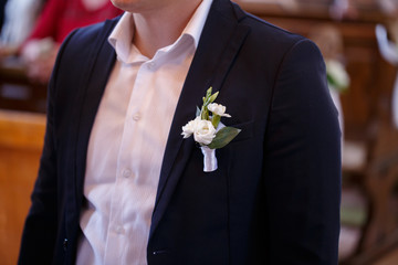 a man in a white shirt and black jacket with a flower