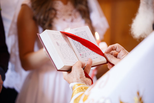 priest holding the Holy Bible with a red ribbon on the wedding ceremony
