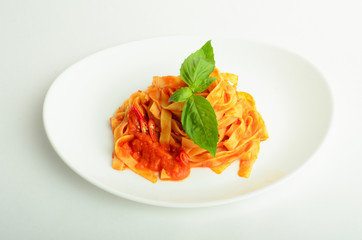 Pasta in tomato sauce  decorated basil on a plate isolated on white background