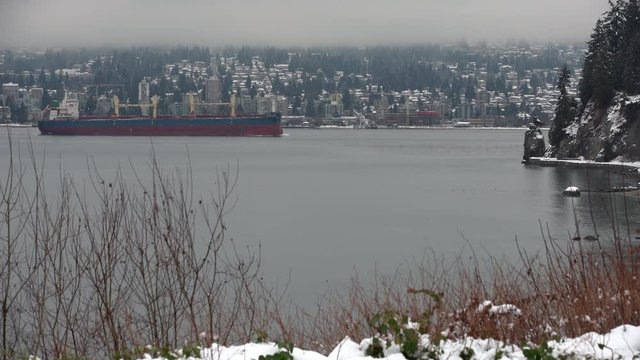 English Bay Snow and Freighter 4K. UHD. A freighter travels into Burrard Inlet from English Bay. In the background is West Vancouver. Vancouver, British Columbia, Canada. 4K. UHD.

