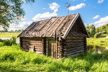 Obraz premium Traditional russian old wooden bath at the bank of river in sunny summer day