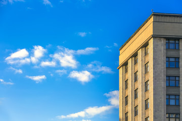 The building of classical architecture, strict and restrained, facing the walls with light limestone. A bright blue sky with small clouds. Copy space for text. Skyscraper, Moscow, Russia.