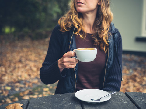 Young woman drinking coffee outside in autumn