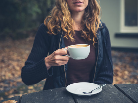 Young woman drinking coffee outside in autumn