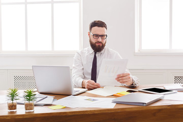 Concentrated businessman read documents in modern white office