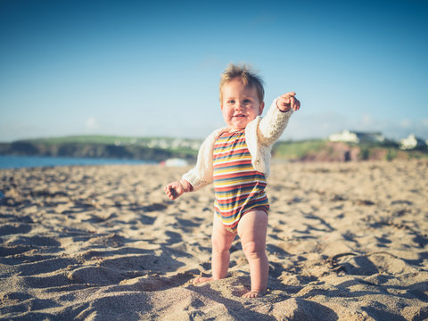 Little baby on beach pointing
