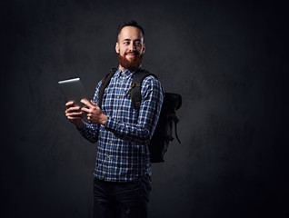 A man holds tablet PC and a backpack.