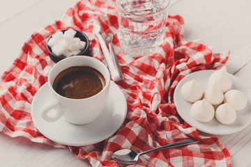 Coffee cup and smartphone on checkered cloth at white wood