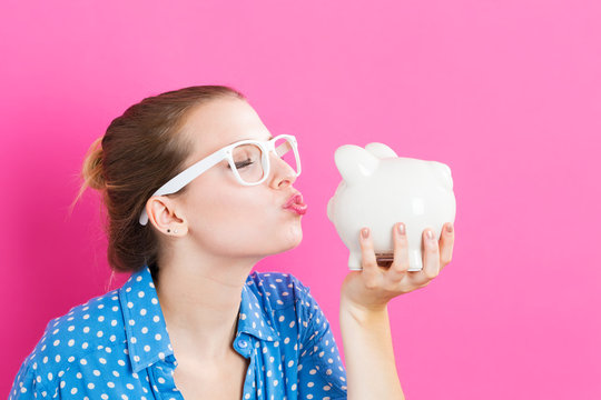 Young woman with a piggy bank on pink background