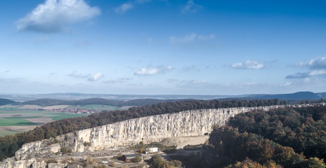 Fototapeta premium Aerial view of a quarry (limestone) with a village in the background