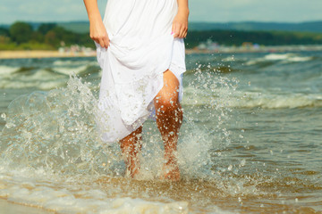 Blonde woman wearing dress walking in water