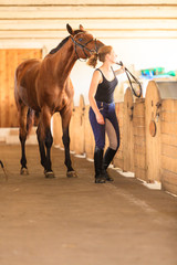Jockey young girl petting brown horse