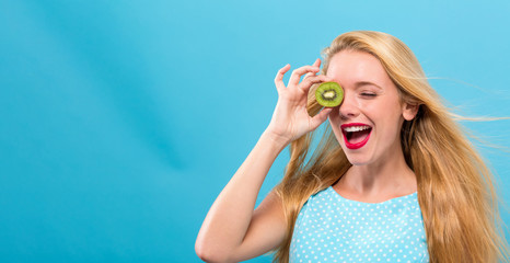 Happy young woman holding kiwis on a solid background