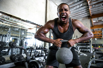 Man shouts and screams pushing hard with dedication and determination lifting heavy kettlebell