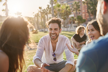 Young man sitting outside with friends laughing