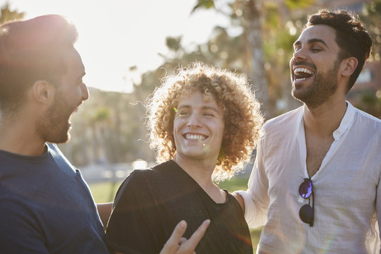 Three young men standing together outside laughing