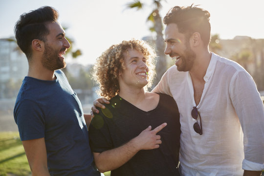Three Male Friends Talking Together Outside Laughing
