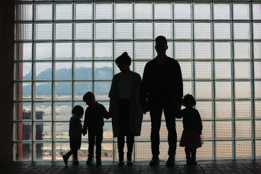Sillouette of family standing together in front of window grid