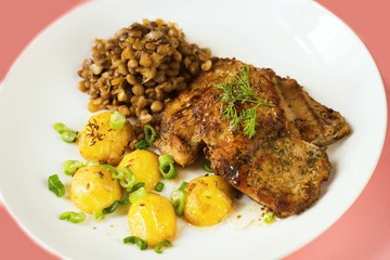 Roasted fish, potato and lentil on white plate.