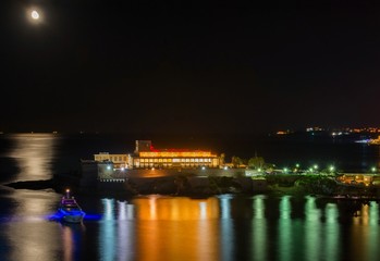 Fototapeta na wymiar Casino at night with light reflection on sea, Malta, St. Georges bay, St. Julians.