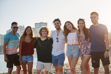 Group of happy friends standing together on beach