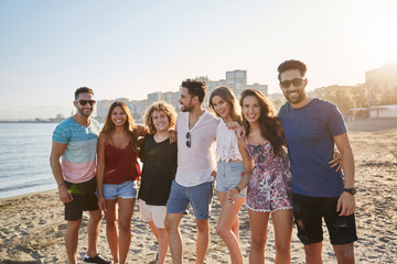 Group of friends standing together on beach smiling