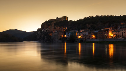 Naklejka premium Vista del pueblo de Miravet (Tarragona), junto al río Ebro en un atardecer dorado